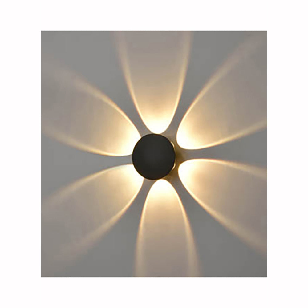 Modern wall light fixture projecting warm yellow petal-shaped light patterns on gray wall