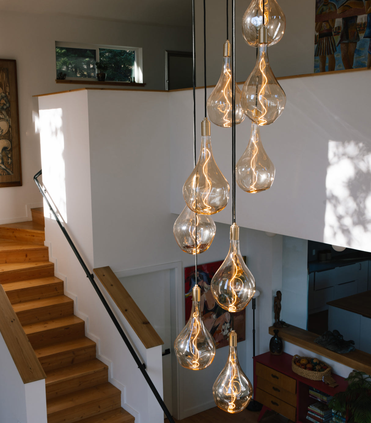 Modern teardrop pendant lights with filament bulbs hanging in a cozy staircase area with wooden steps