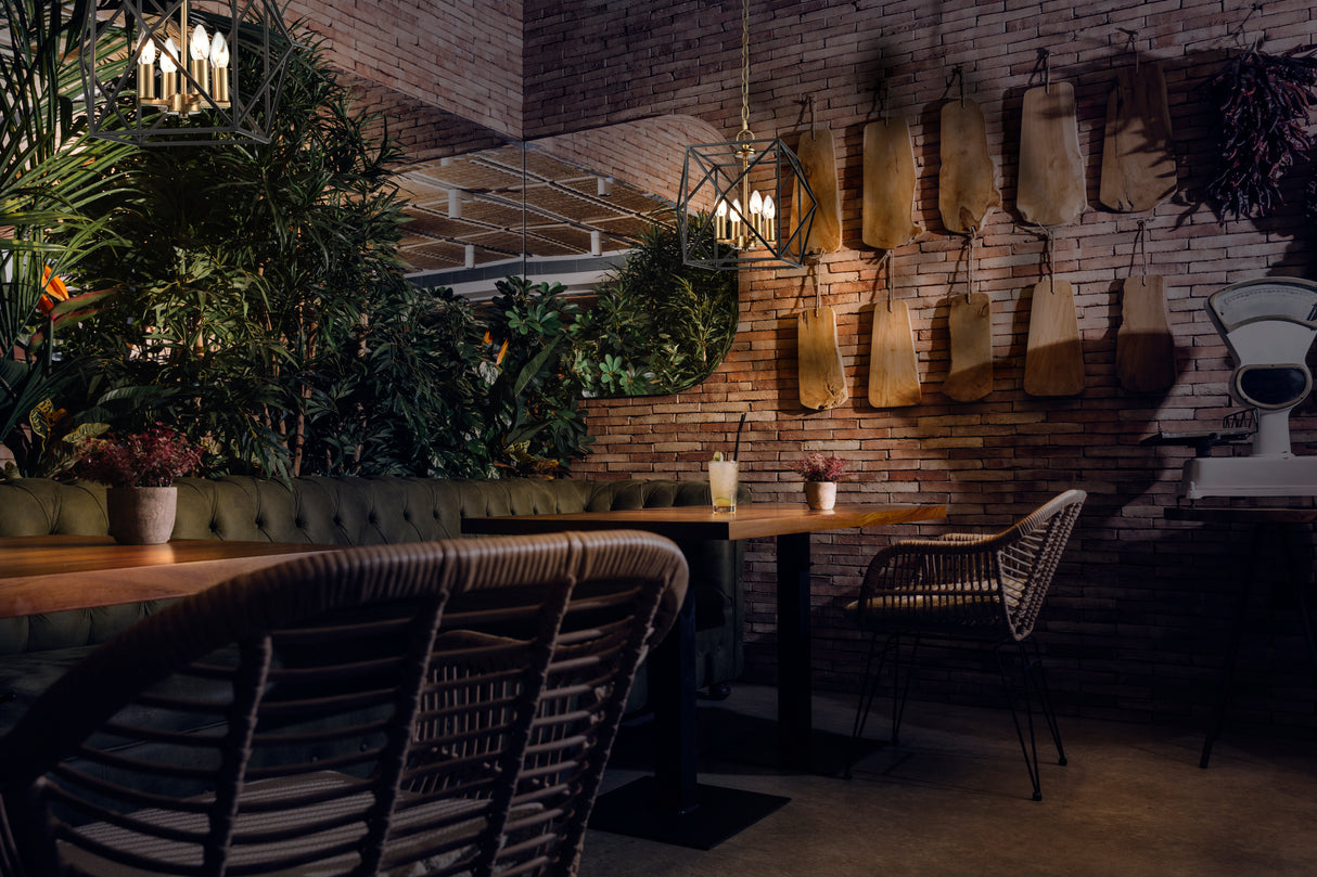 Cozy restaurant interior with wooden tables, wicker chairs, green plants, brick walls, decorative hanging boards, and a vintage scale