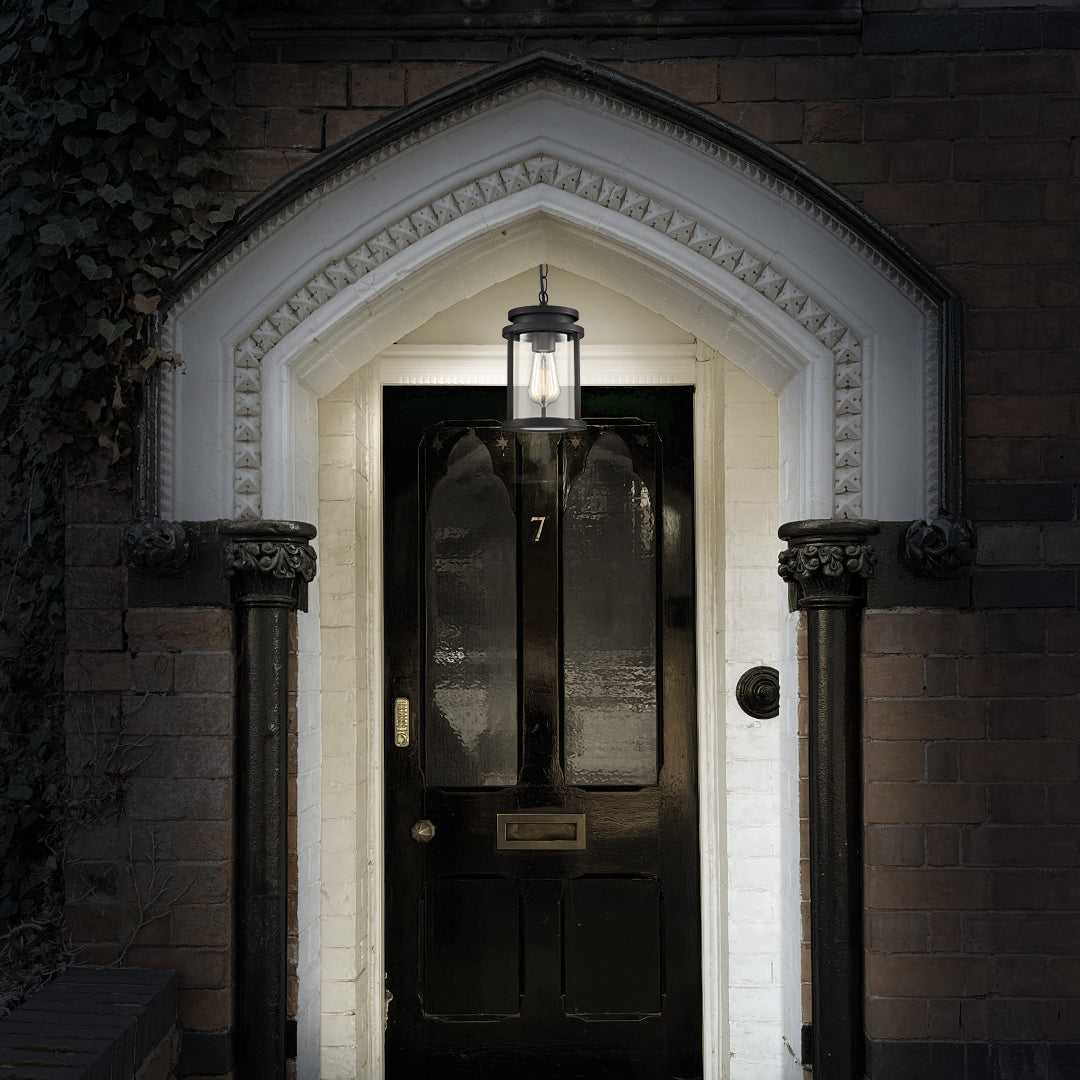 Black front door with number 7 under arched white brick entrance and hanging lantern light