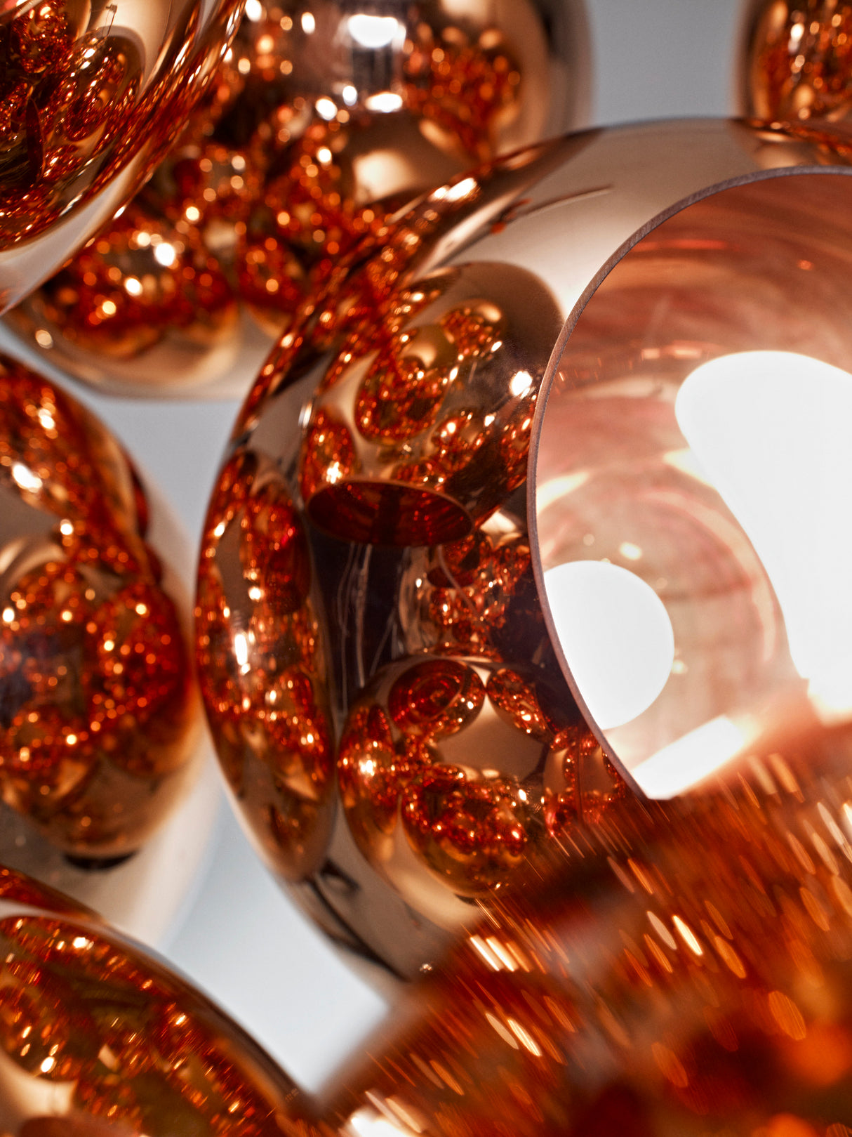 Close-up of modern copper lampshades with shiny reflective surfaces and warm lighting