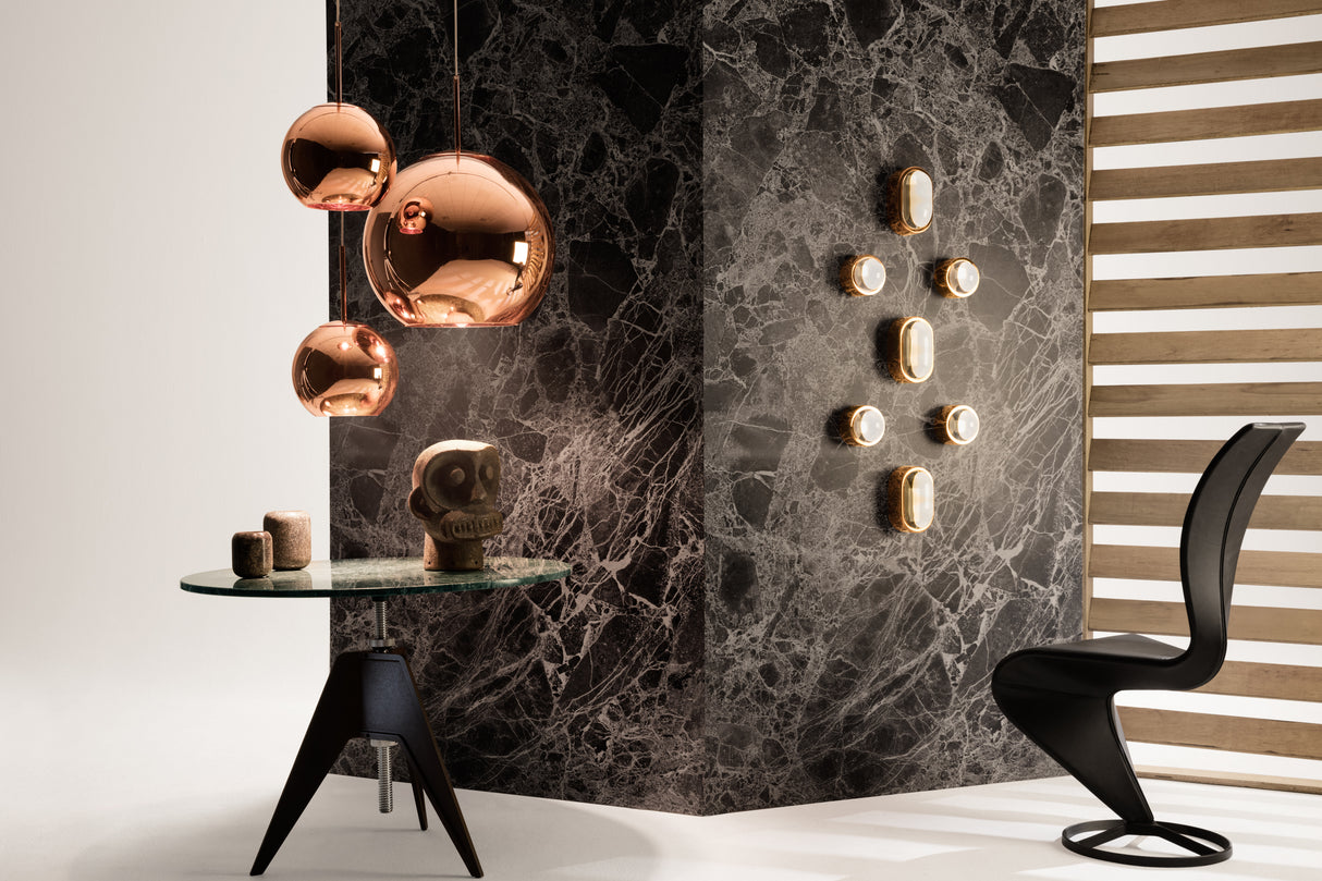 Modern interior with black sculptural S-chair, black marble table, copper pendant lights, and abstract wall decor