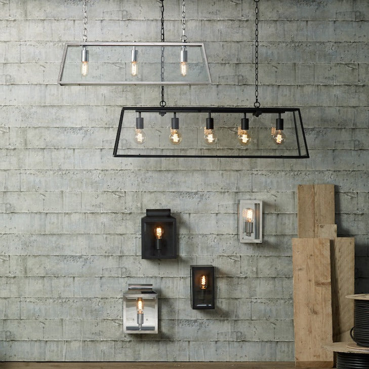 Modern industrial light fixtures including stainless steel and black metal pendant lights and wall sconces on concrete wall