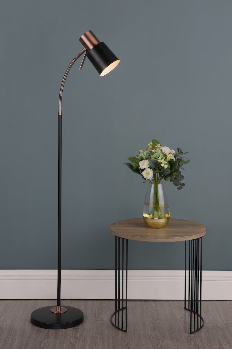 Black and copper adjustable floor lamp beside wooden side table with glass vase of flowers
