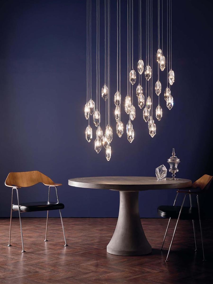 Modern dining room with crystal cluster pendant lights, round concrete table, and wooden chairs