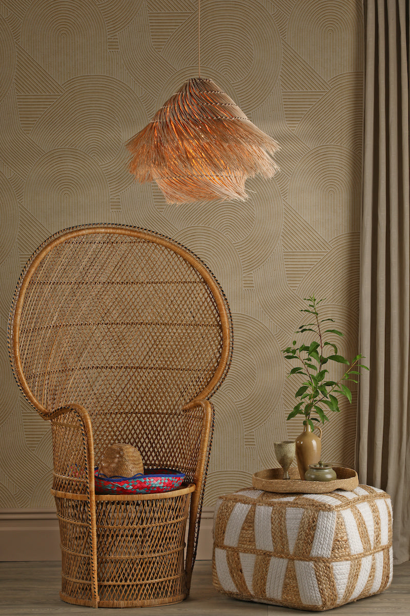 Woven rattan peacock chair with colorful cushion, fringed pendant light, pouf, and decorative tray in boho room