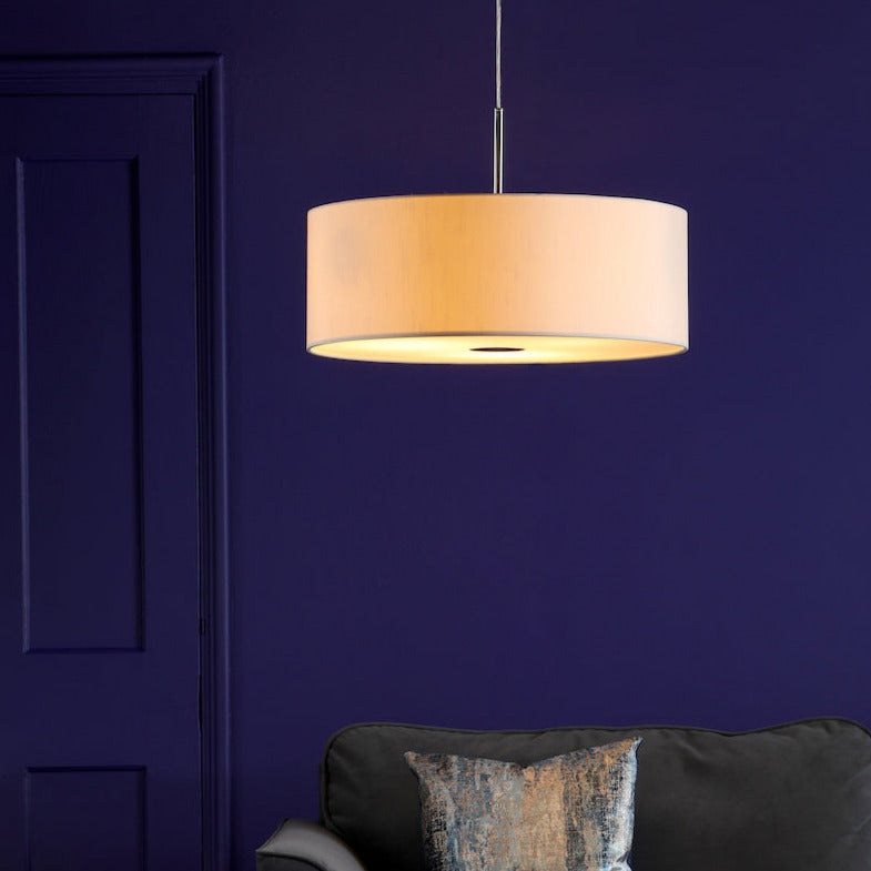 Ecru 3-light drum pendant ceiling lamp hanging above a dark sofa with patterned cushion against a deep purple wall