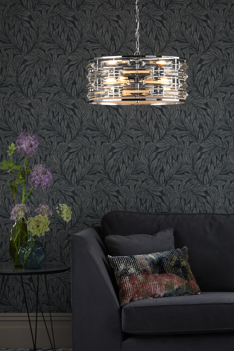 Modern 6-light crystal polished chrome pendant lamp above dark sofa with patterned cushions and floral wallpaper