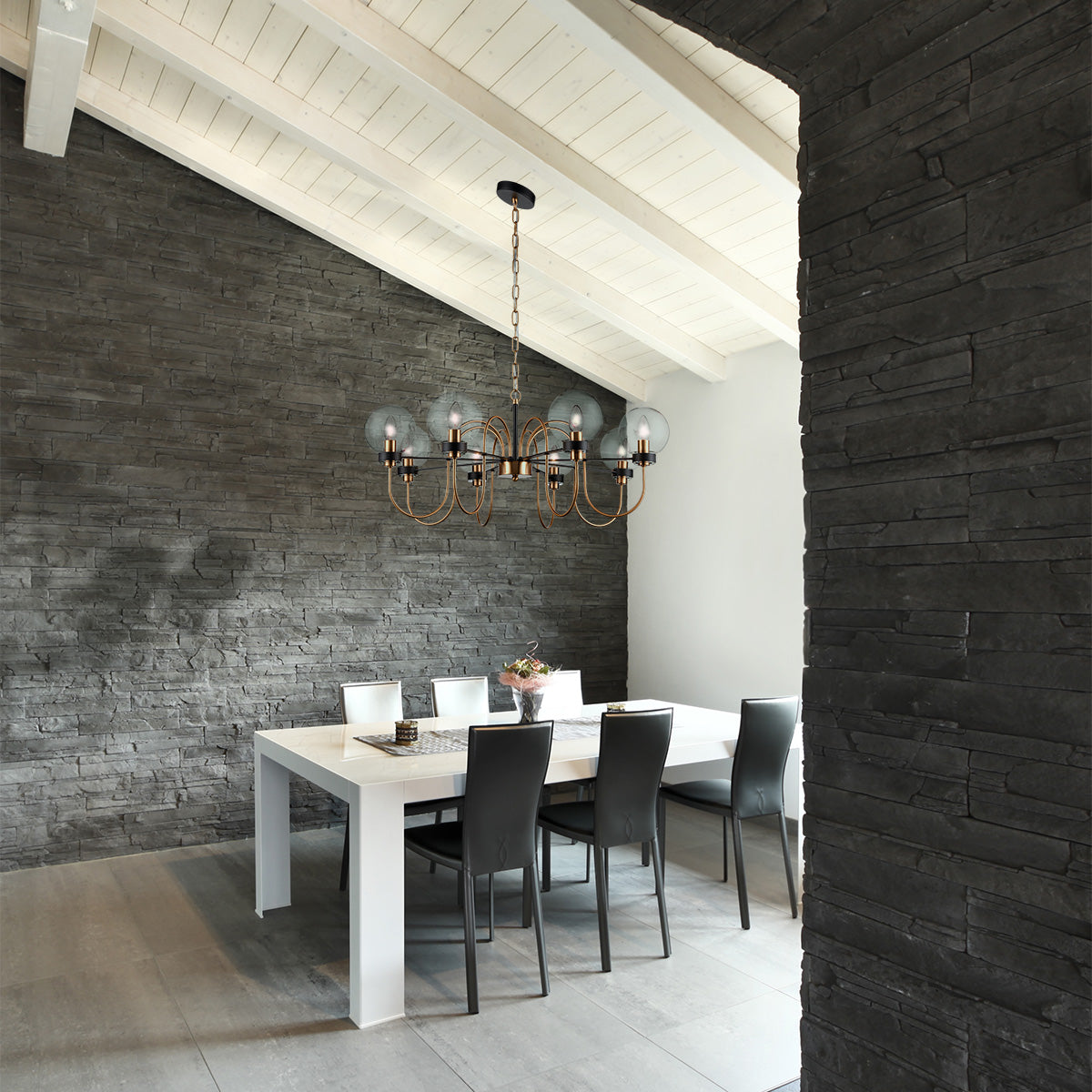 Modern dining room with white table, black and white chairs, black stone accent wall, and chandelier