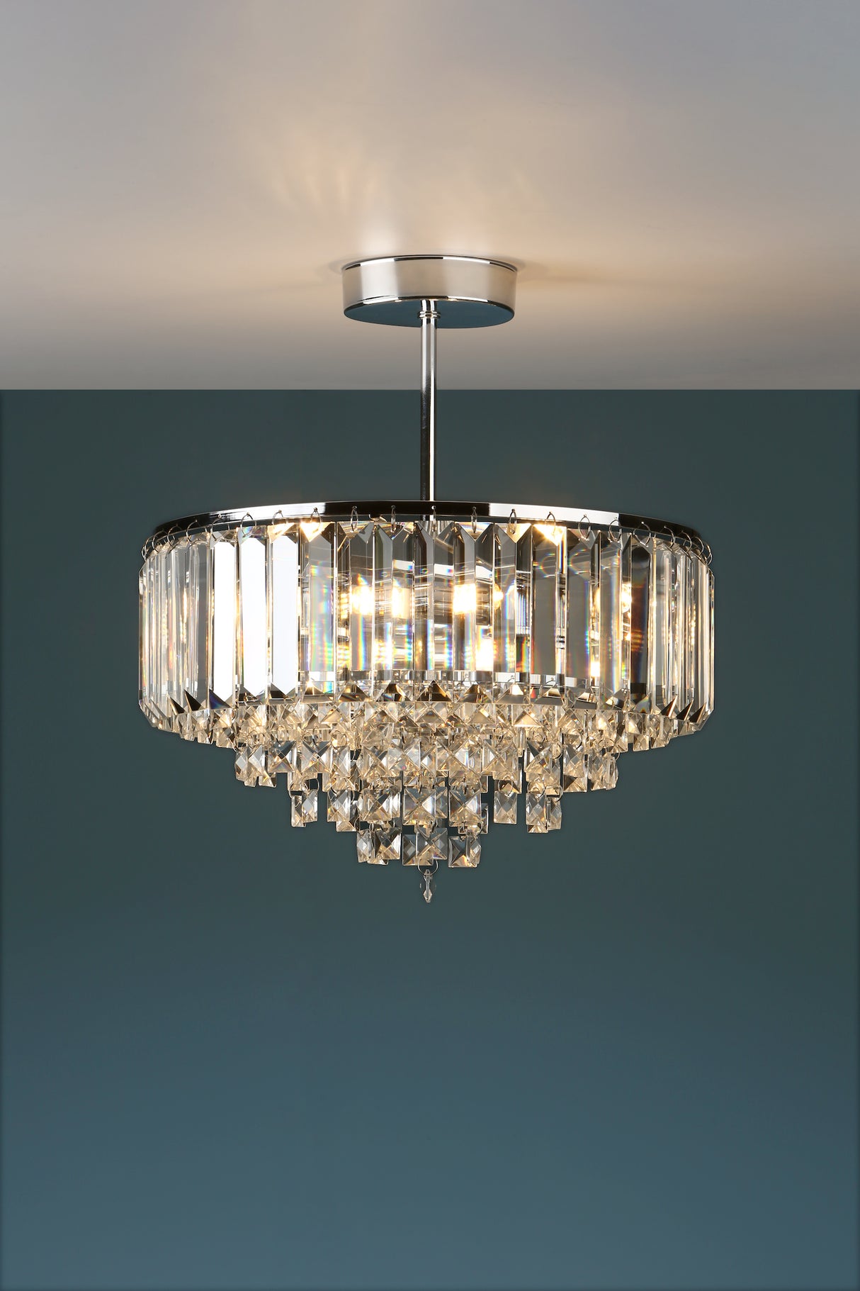 Modern crystal chandelier ceiling light with rectangular prisms and silver finish against teal wall
