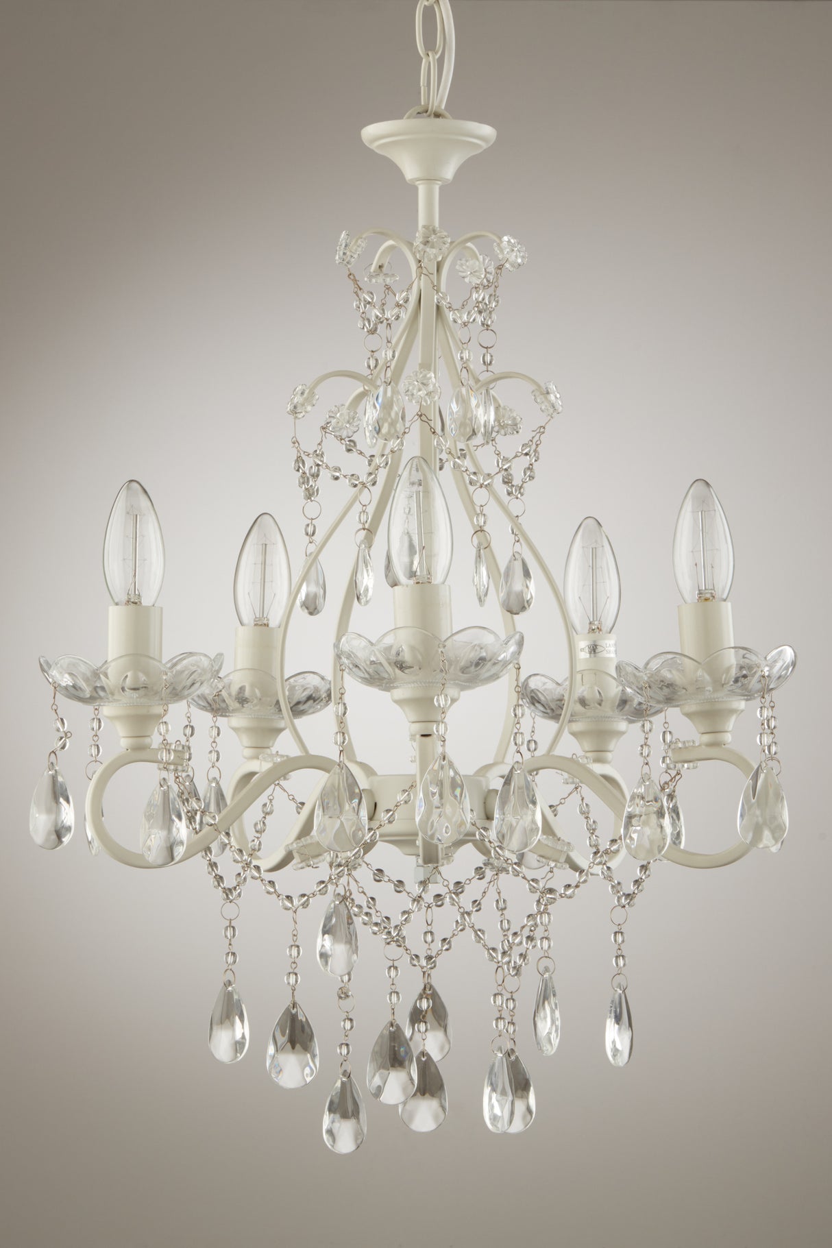 Elegant white metal chandelier with five candle-style bulbs and hanging crystal teardrops