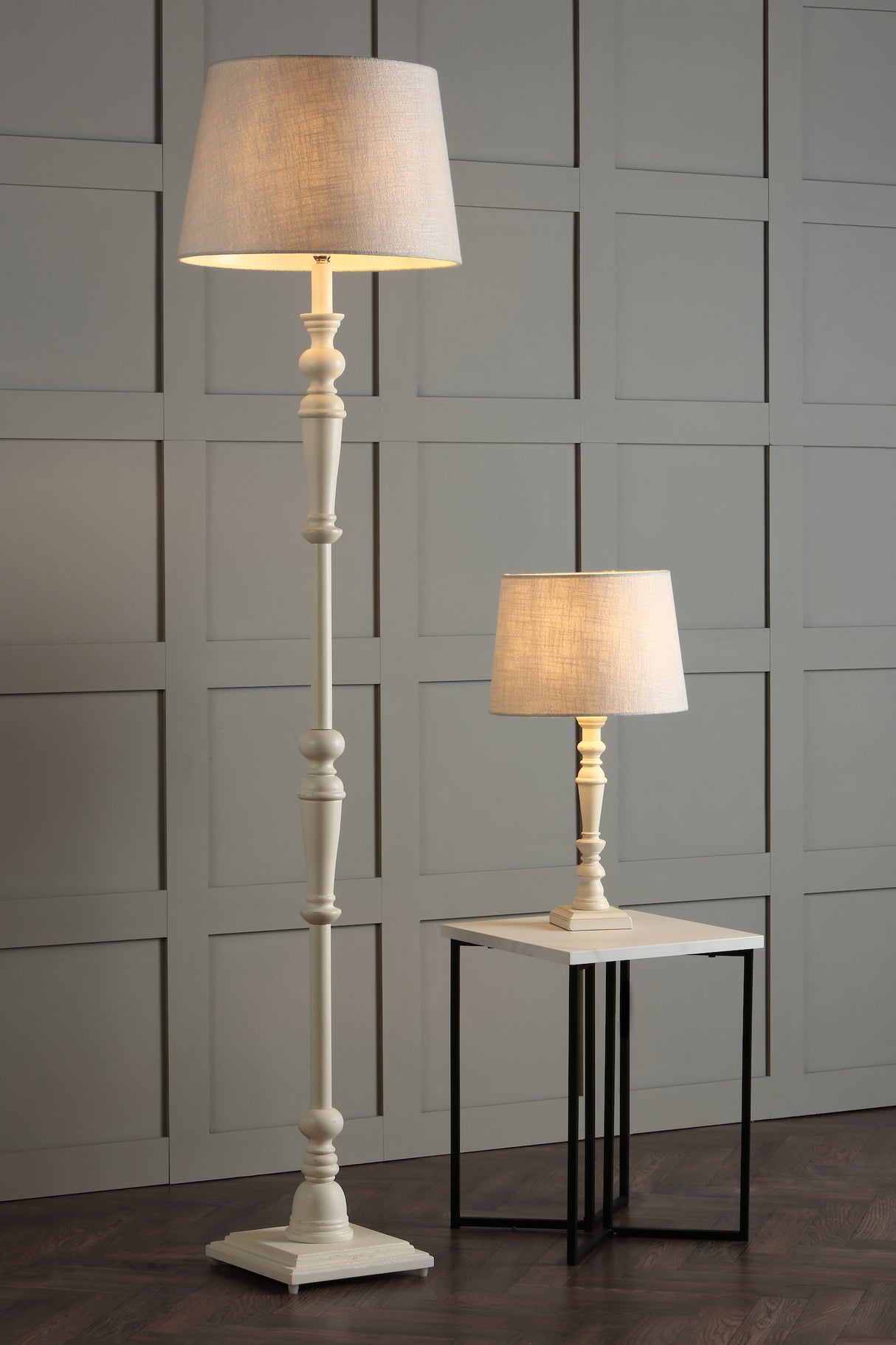 Tall white floor lamp and shorter table lamp with beige fabric shades on modern side table