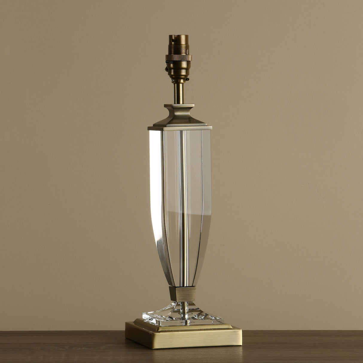 Modern glass and brass table lamp base with geometric design on wooden surface