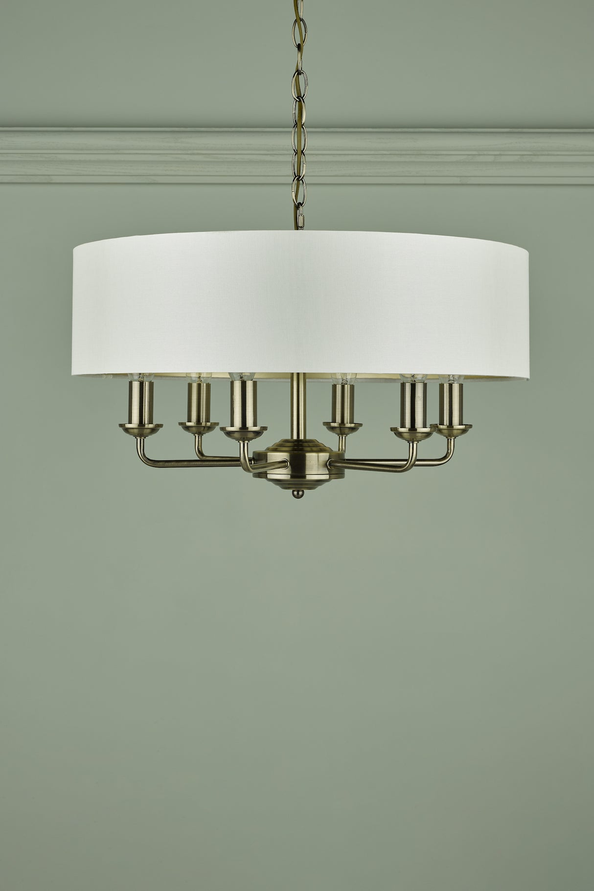 Modern brass chandelier with six candle-style lights and white fabric drum shade hanging from ceiling
