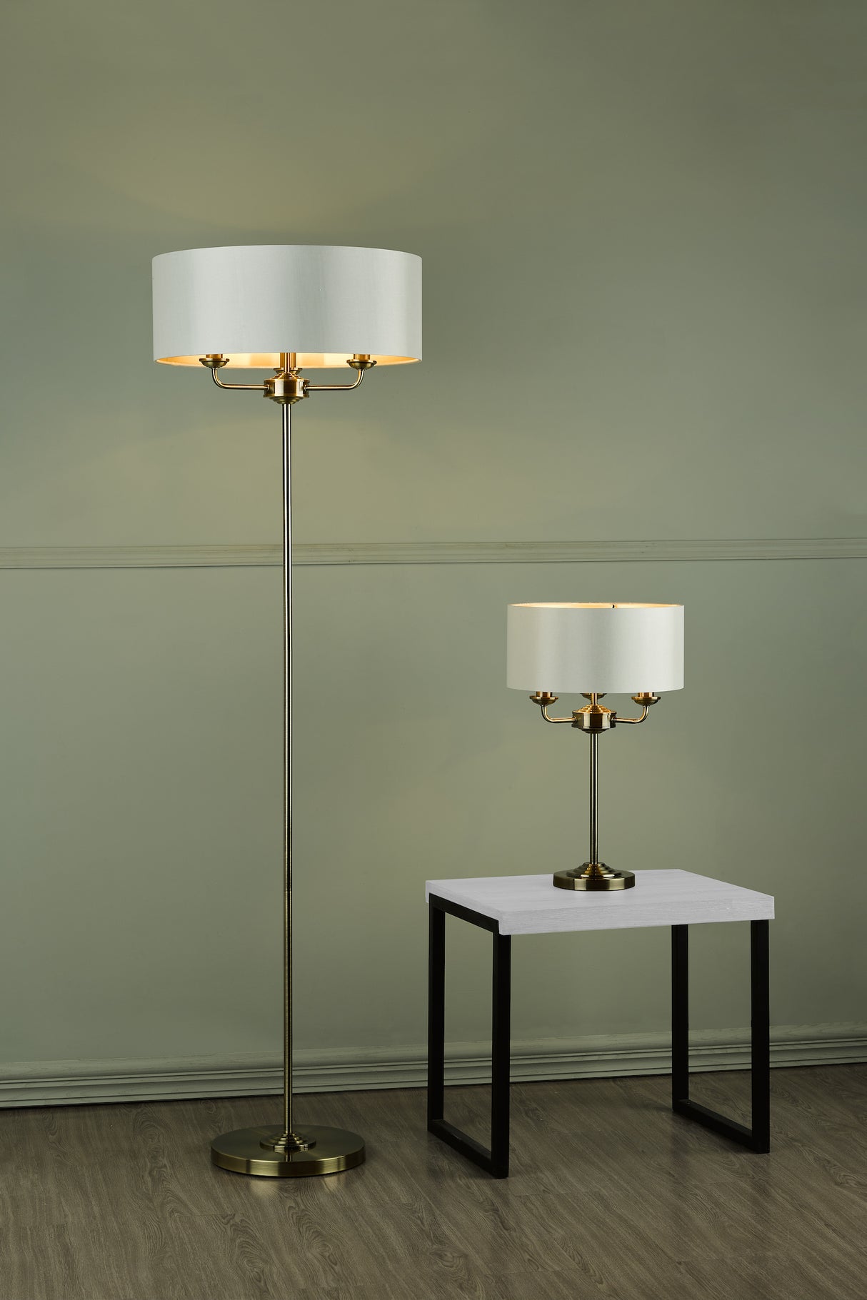Modern brass floor lamp and matching table lamp with white drum shades in minimalist room