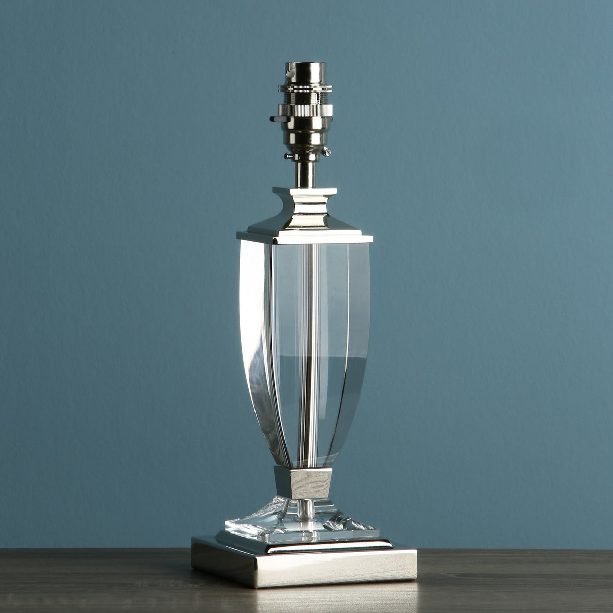 Elegant table lamp base with silver metal and clear glass design on wooden surface