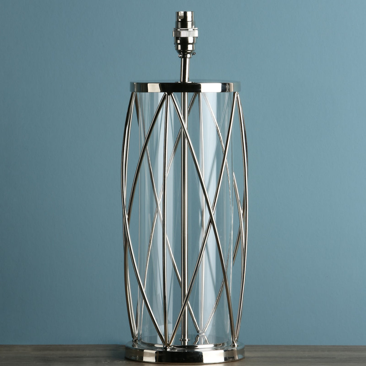 Modern table lamp base with silver metal wire cage and glass cylinder on wooden surface