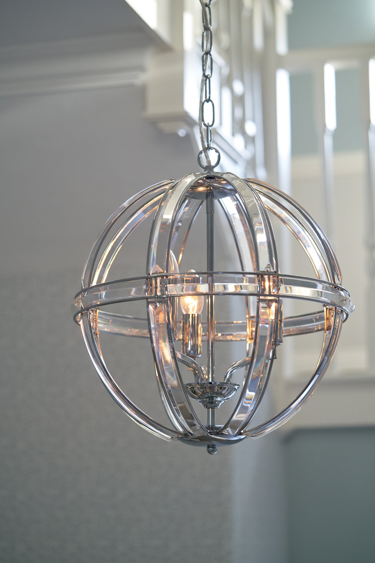Modern spherical chandelier with clear glass and metal rings, hanging indoors