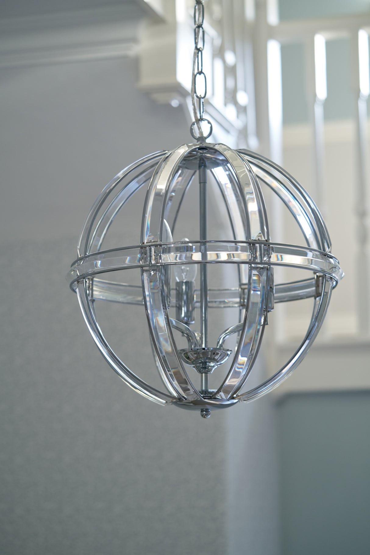 Modern spherical chrome pendant light fixture hanging indoors with visible bulbs
