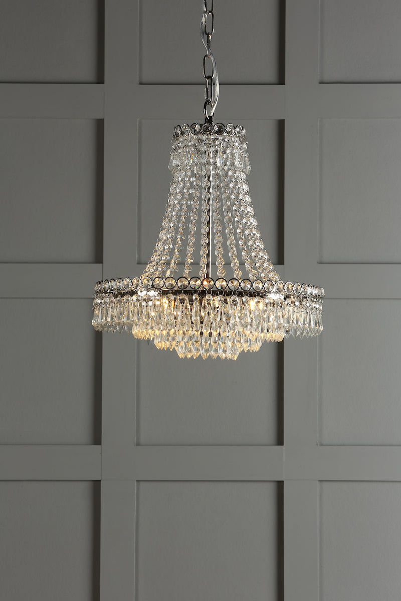 Elegant crystal chandelier pendant light with hanging prisms against gray paneled wall