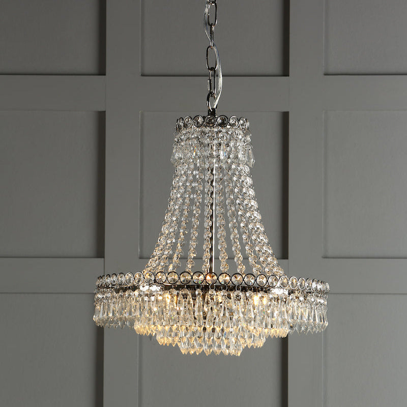 Elegant crystal chandelier with hanging glass beads and metal frame against gray paneled wall