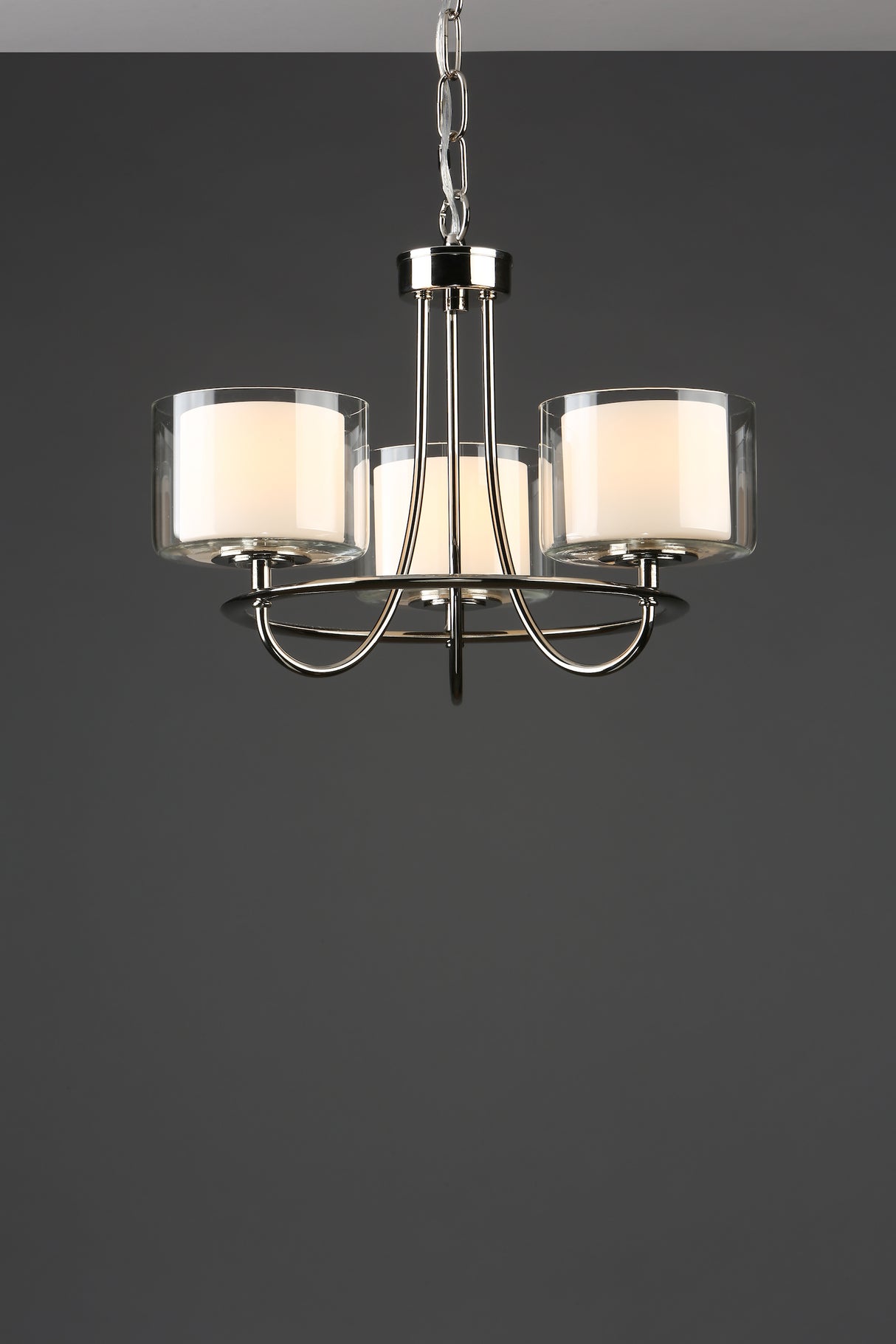 Modern three-light chandelier with silver metal frame and frosted glass shades on dark background