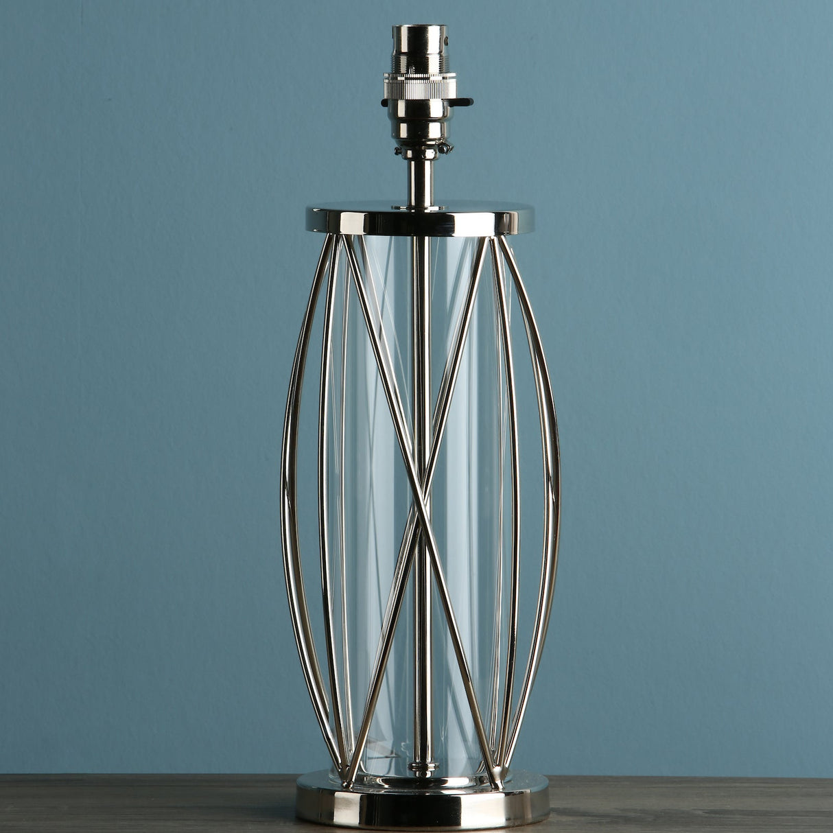 Modern glass and metal table lamp base with geometric wireframe design on wooden surface