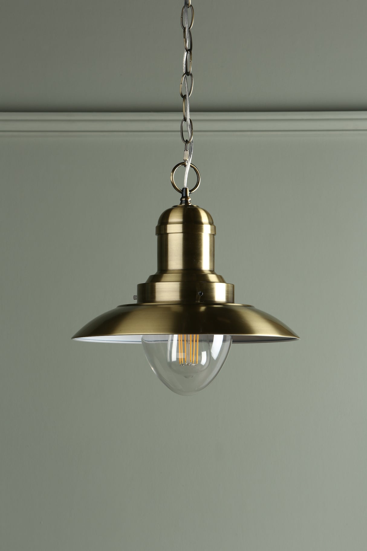Vintage style brass hanging pendant light with clear bulb and chain suspension against gray wall