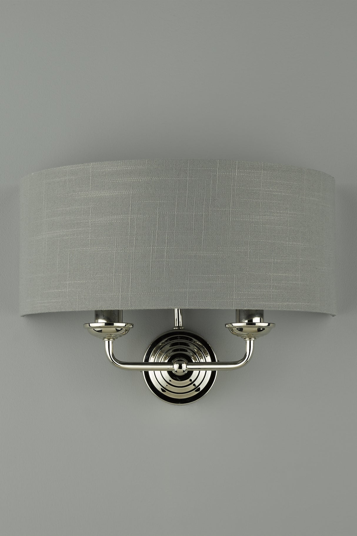 Modern silver wall sconce with textured gray fabric drum shade on light gray wall