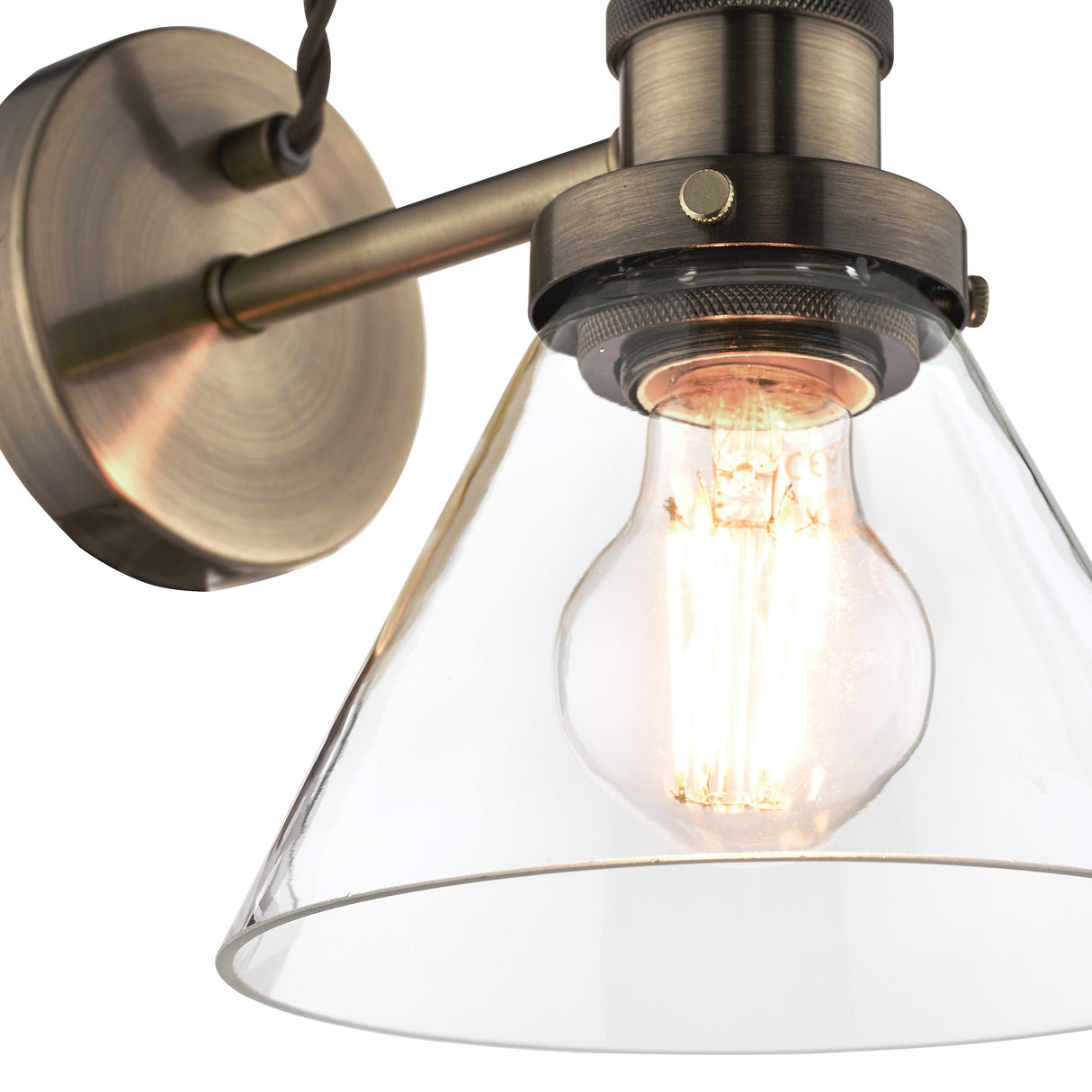 Vintage wall light fixture with clear glass shade and Edison bulb in antique brass finish