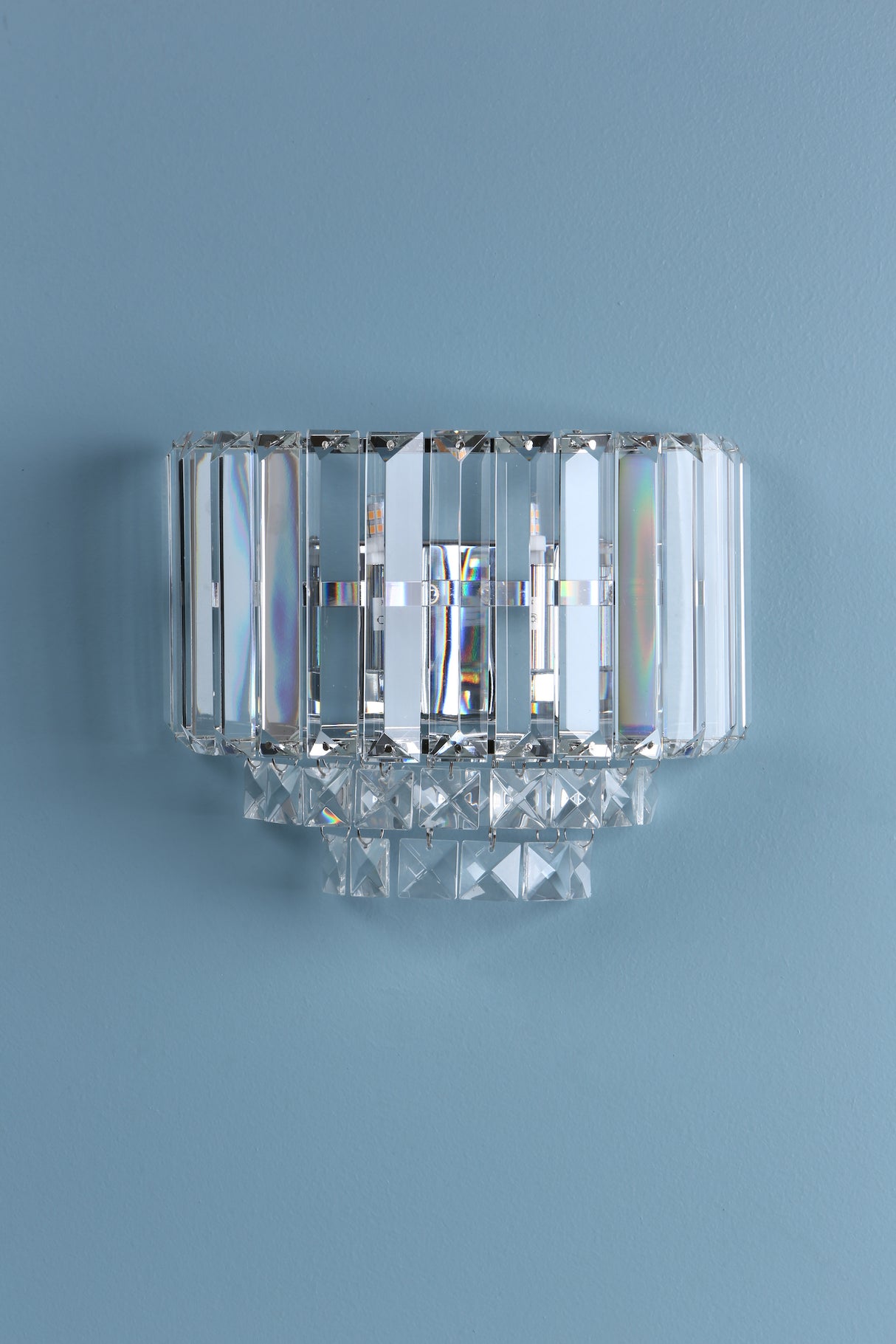 Modern crystal wall sconce light fixture with rectangular prisms on blue wall