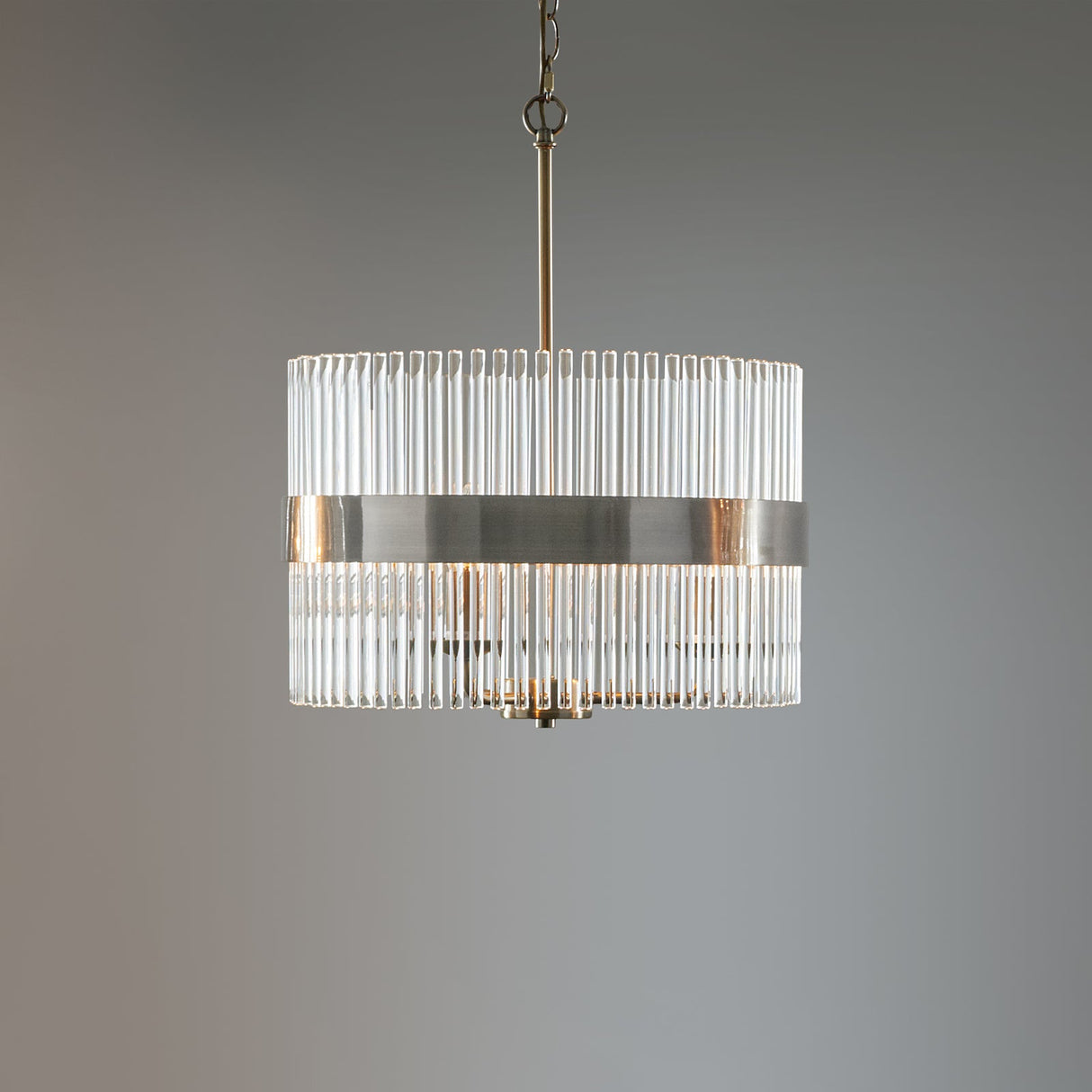 Modern cylindrical chandelier with vertical glass rods and brushed metal band hanging on chain