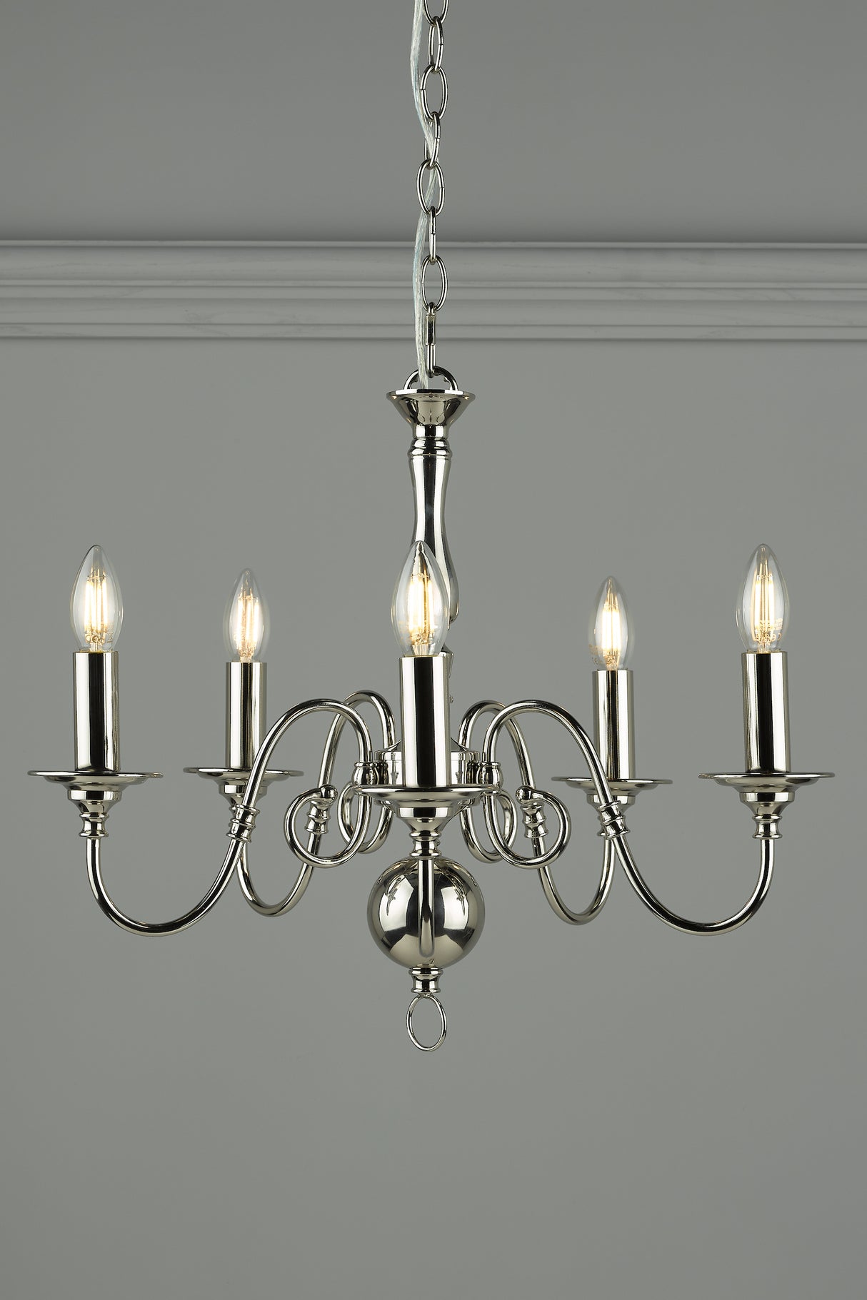 Modern silver chandelier with five candle-style LED bulbs hanging on chain against grey wall