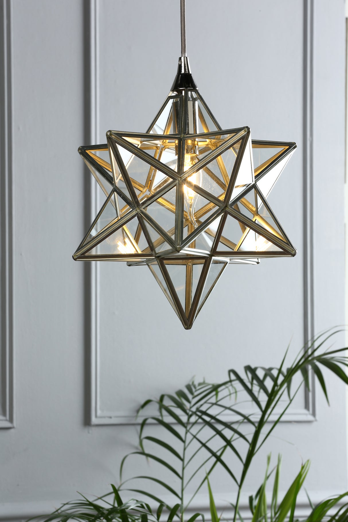 Modern Moravian star pendant light with glass and brass frame hanging by gray cord