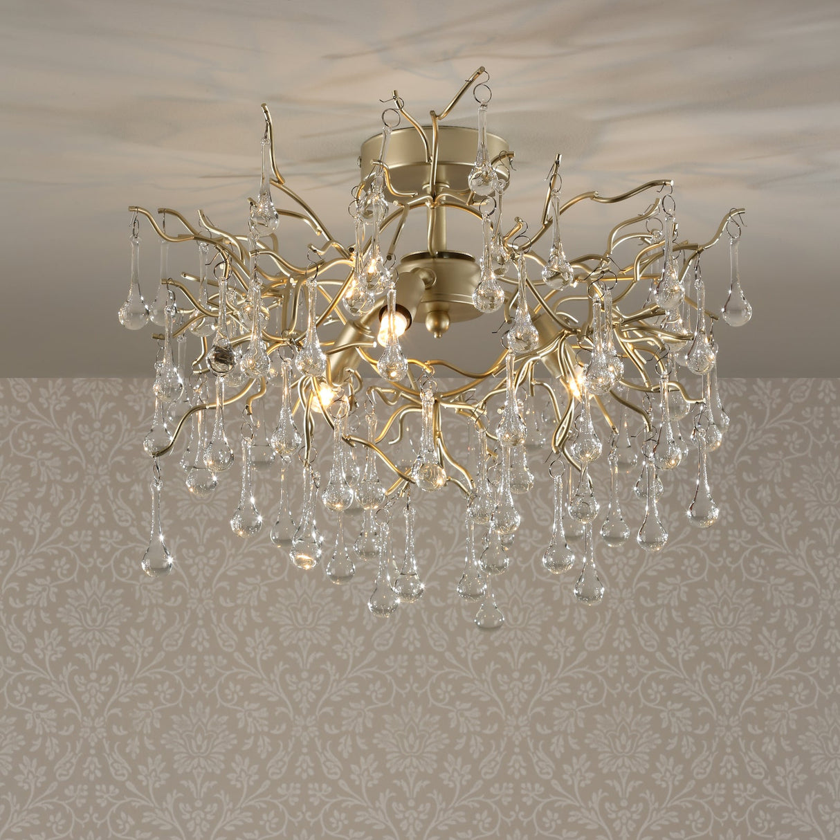 Modern chandelier with gold branches and hanging glass teardrop crystals on ceiling