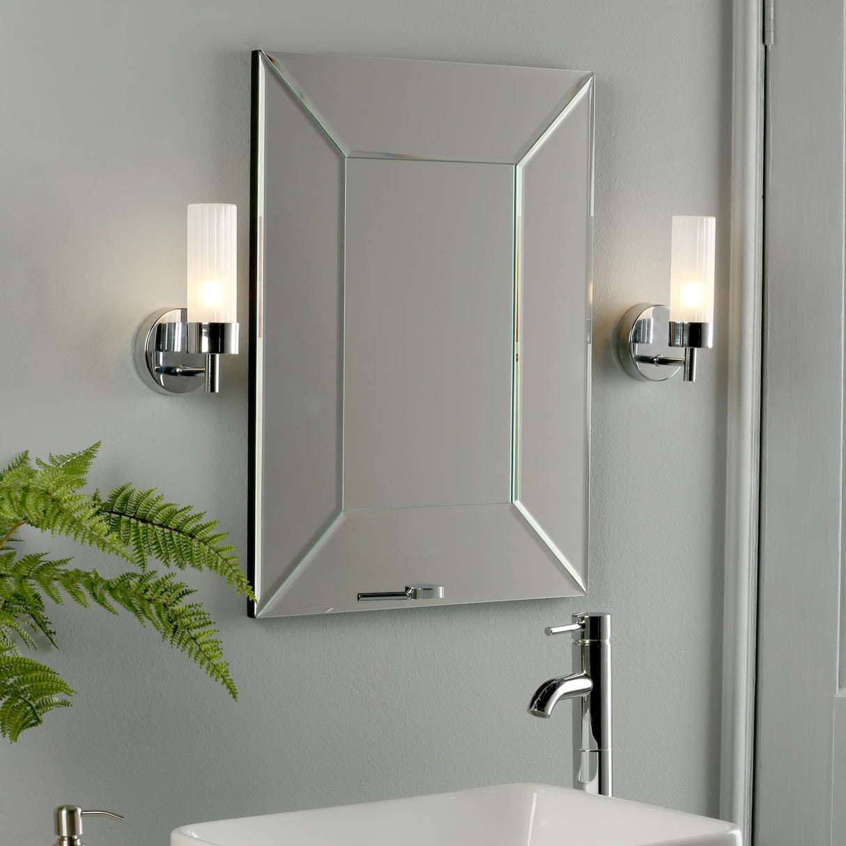 Modern bathroom with square mirrored medicine cabinet, chrome faucet, wall sconces, and green fern