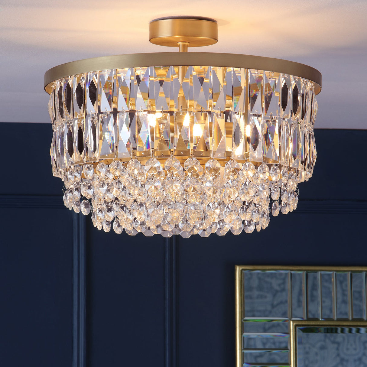 Elegant crystal chandelier with gold frame and hanging glass prisms illuminating a dark blue room