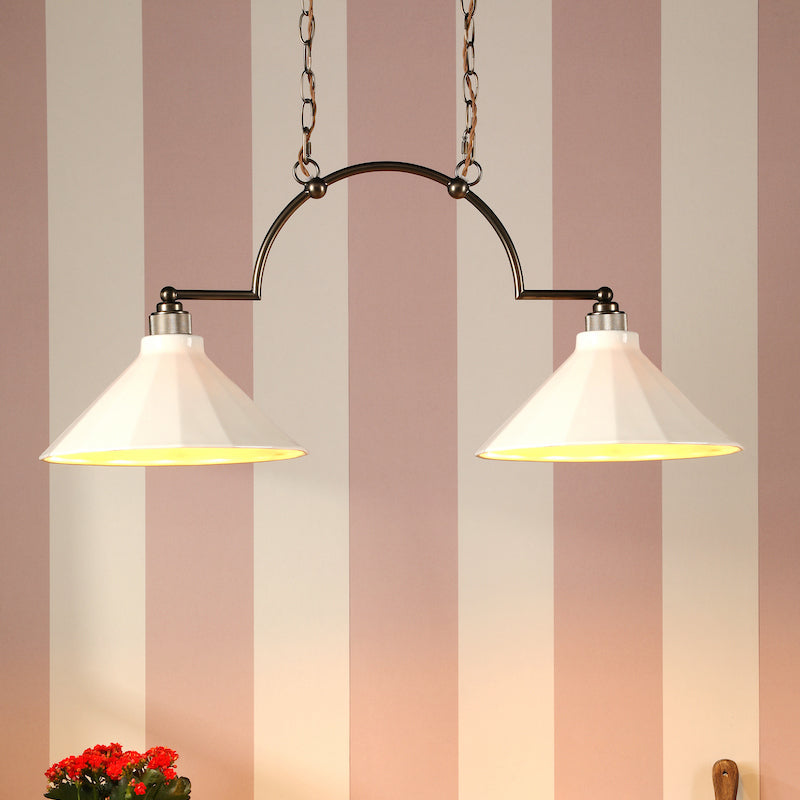 Two pendant lights hanging above a wooden shelf with decorative items against a striped wall.