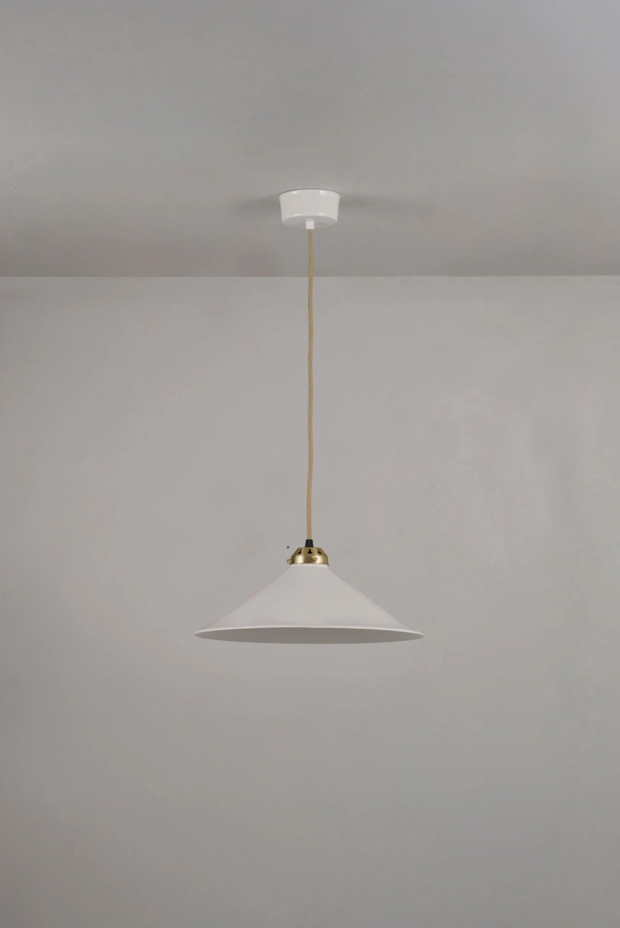 Pendant light with white shade and gold fixture on a plain gray background