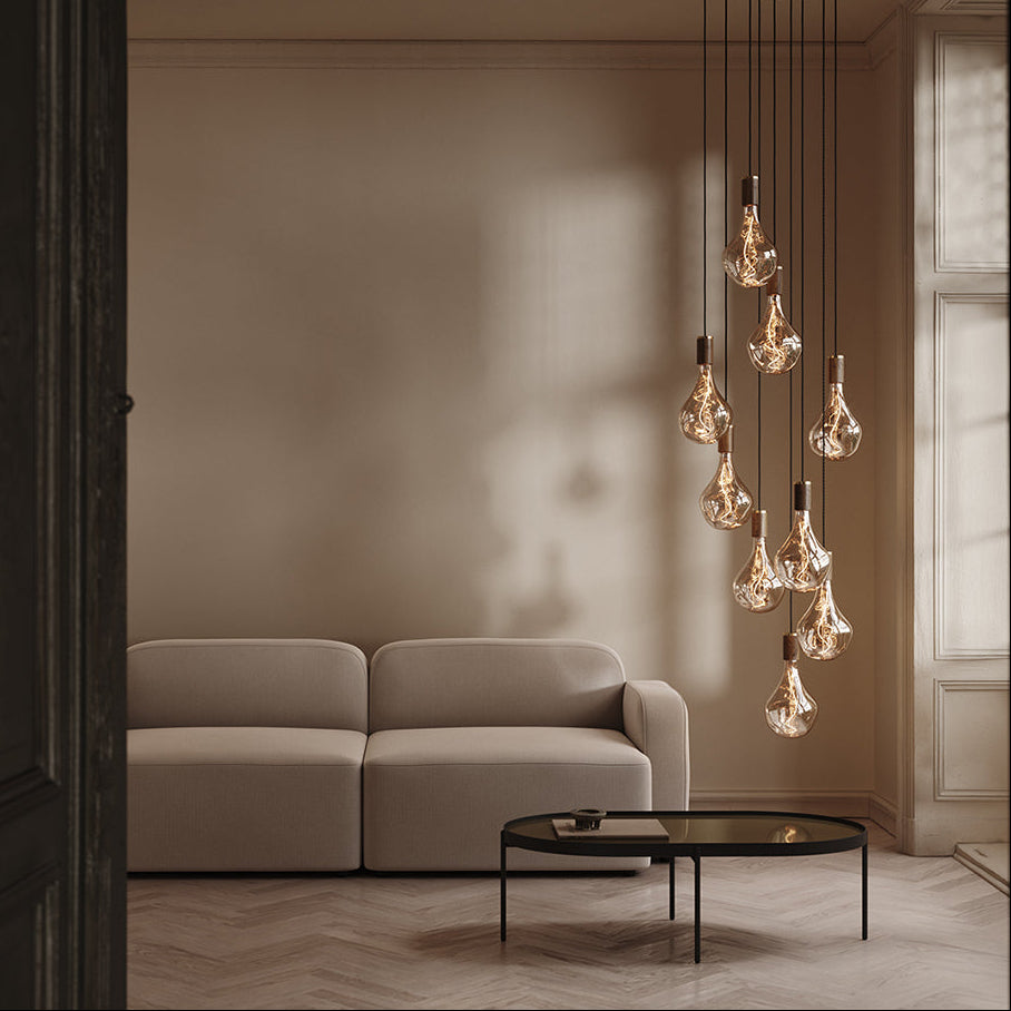 Modern living room with a beige sofa, glass coffee table, and hanging pendant light fixture.