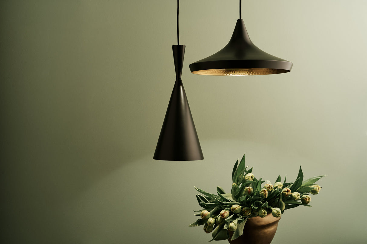 Tom Dixon black pendant LED lights with green tulips in a brown vase on olive wall background