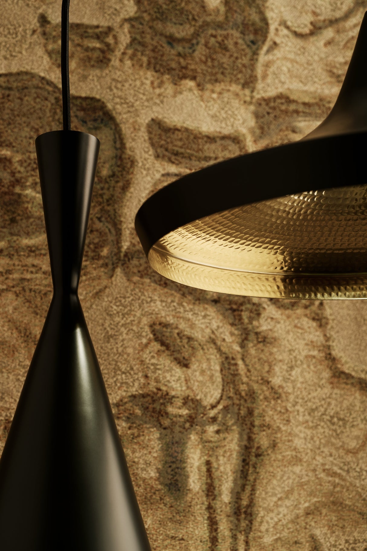 Close-up of black Tom Dixon Beat Wide Pendant LED lamp with hammered brass interior against textured beige wall