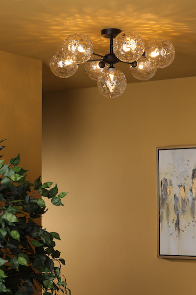 Matt black semi-flush ceiling light with six clear textured glass globes in modern room