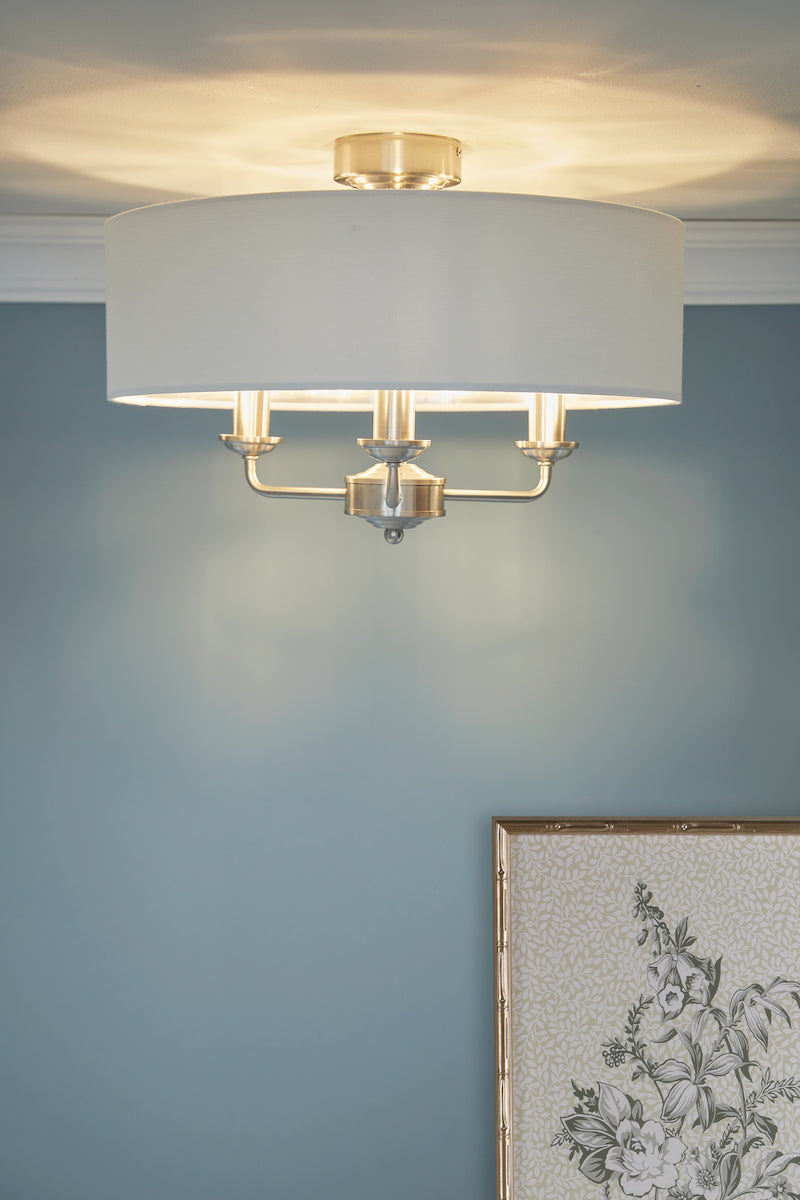 Modern 3-light semi-flush ceiling light with satin nickel finish and white fabric shade on blue wall