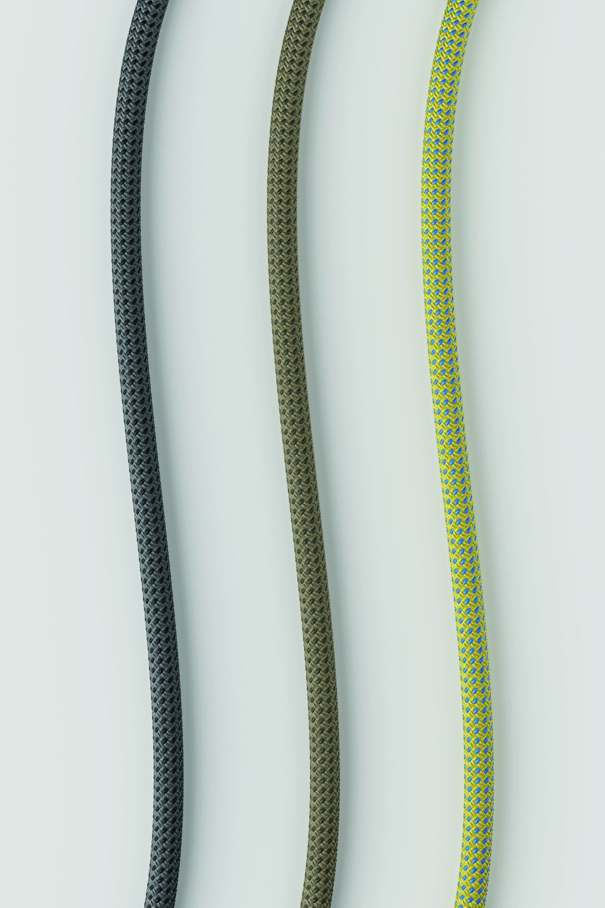 Close-up of three hanging textile cords in black, olive green, and yellow-blue weave