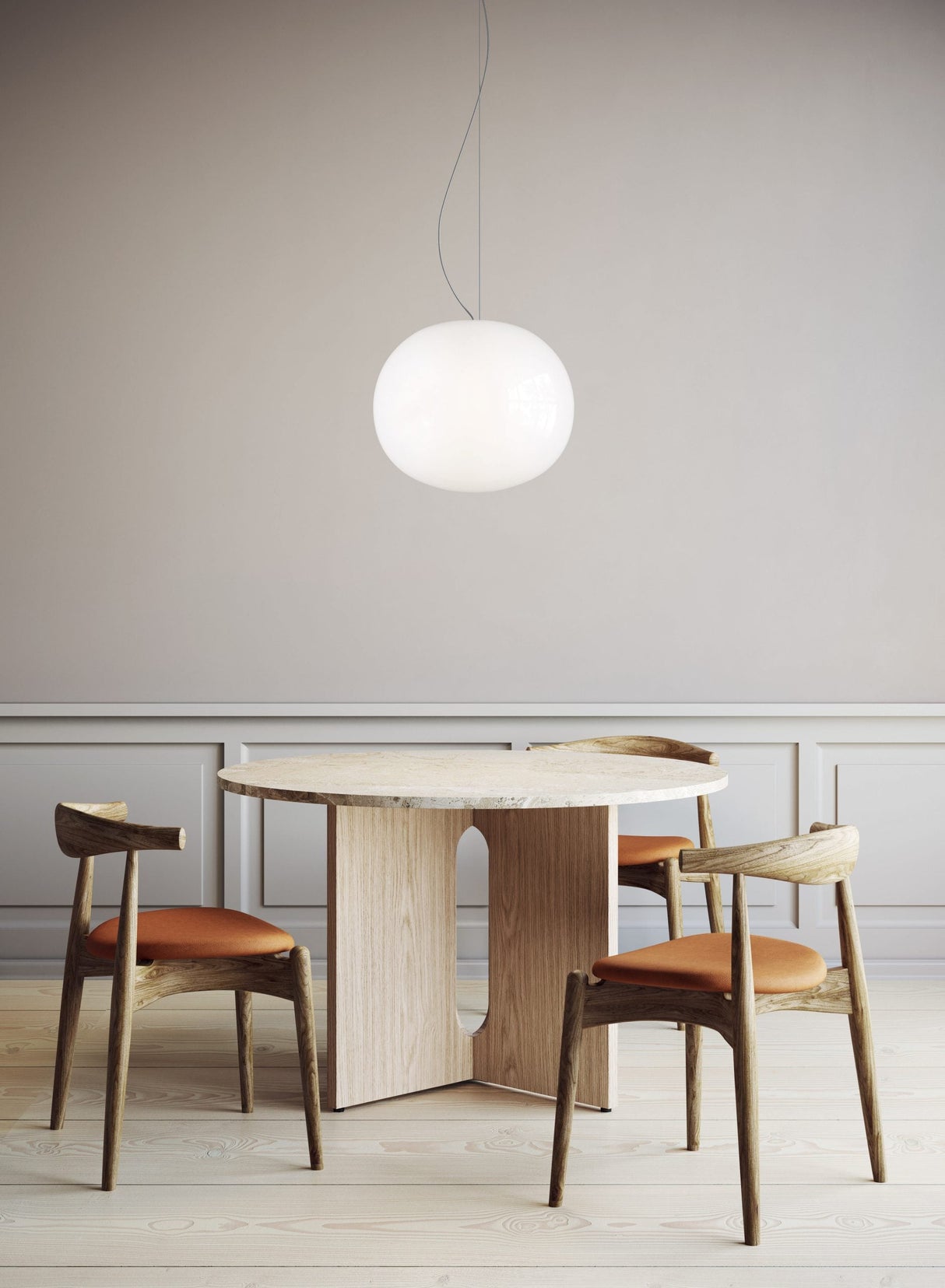 Modern dining room with round wooden table, three wooden chairs with orange cushions, and white pendant light