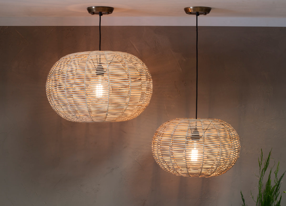 Two large natural wicker round pendant lights with exposed bulbs hanging from ceiling in a warm home setting
