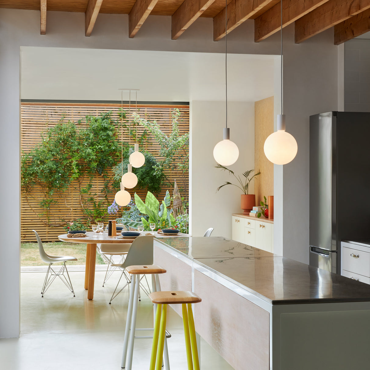 Modern kitchen and dining area with Tala alumina triple pendant sphere lights and open garden view