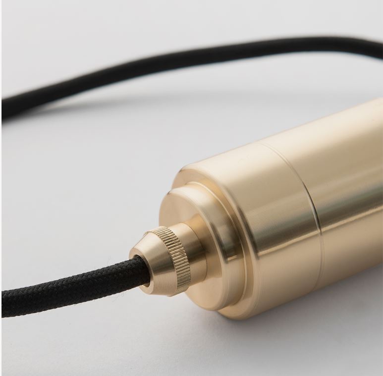 Close-up of turned brass pendant light fitting with textured black cord on white background