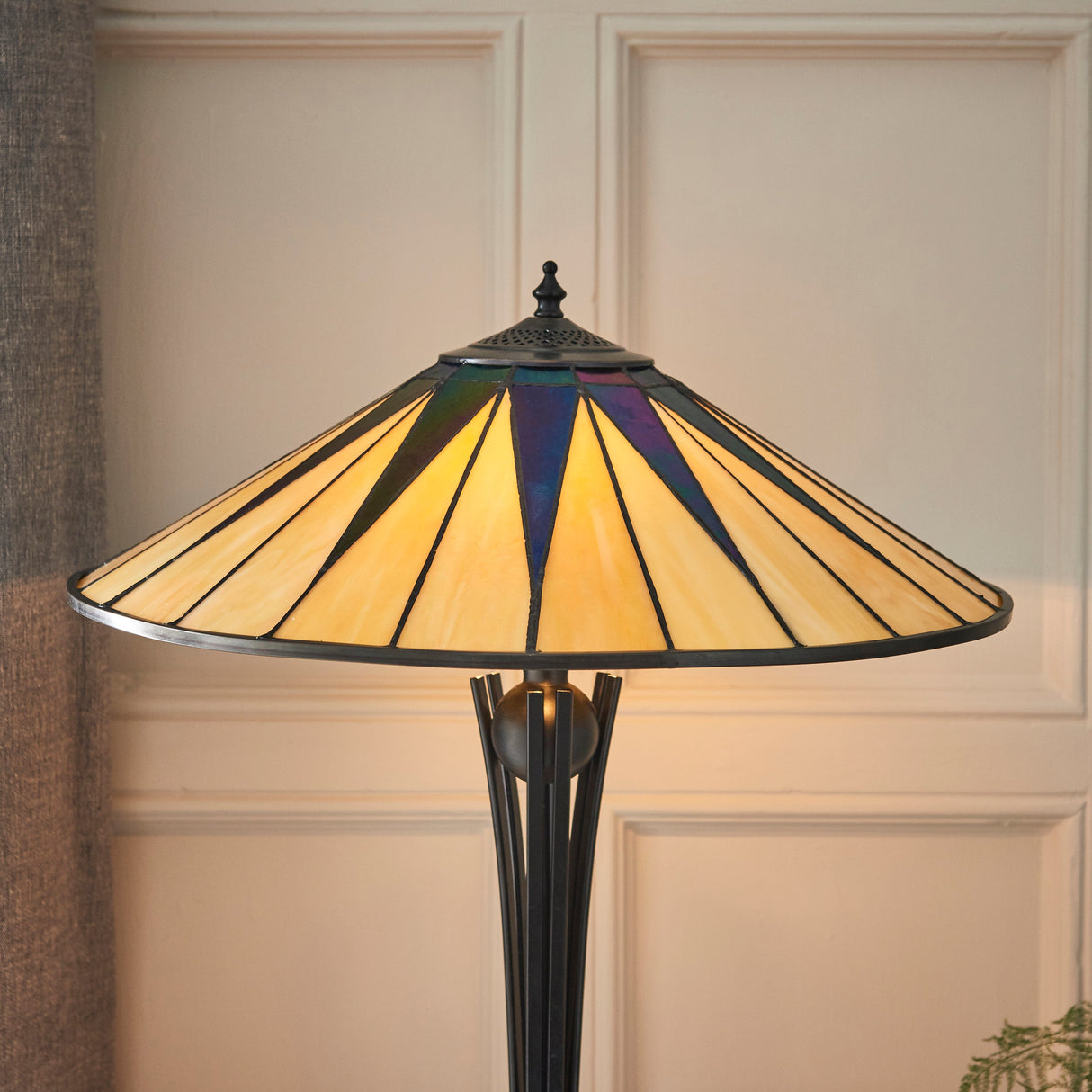 Tiffany-style dark star stained glass table lamp with black metal stand in cozy interior